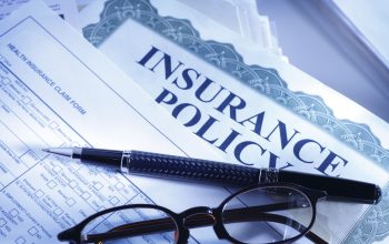 A pen and a pair of glasses on a health insurance policy claim form.