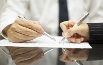 Business man is pointing woman where to sign document